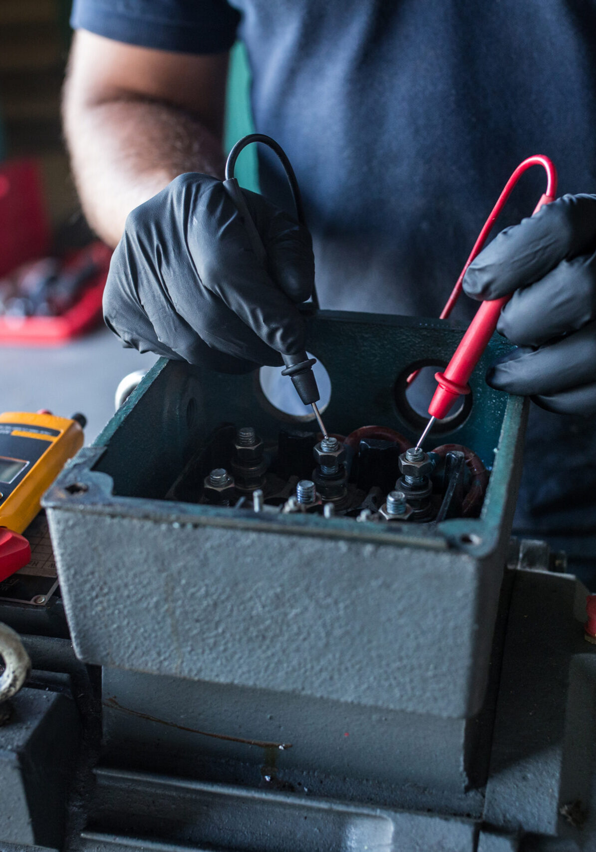 close-up of a mechanic using a multimeter to test an electric motor coil from a compressor engine